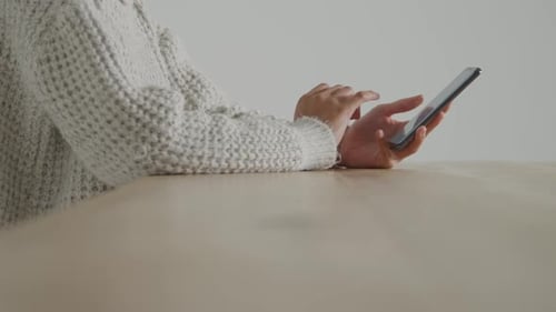 Person Using Mobile Phone at Table Indoors