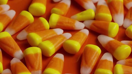 Colorful Candy Corn Pieces on Bright Orange Surface