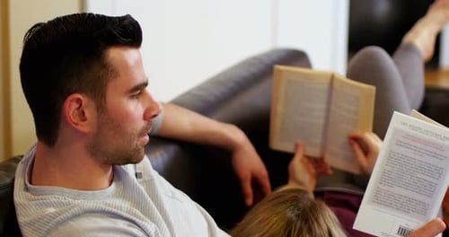Couple lying on sofa and reading books