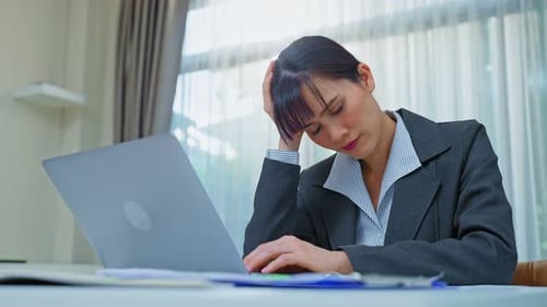 Woman Working on Laptop Looks Tired and Stressed