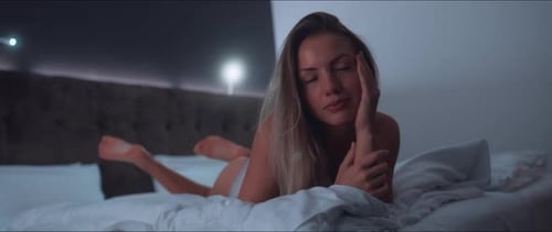 Sensual Woman Lying on Bed in Dim Lighting