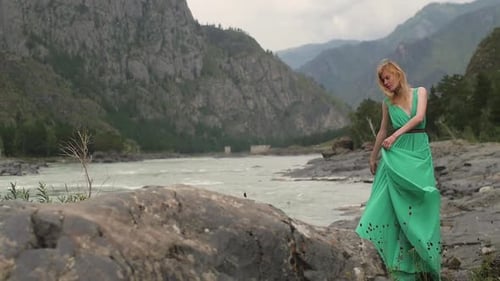 Young Woman in a Long Flowing Dress on the Background of the River and Mountains. Coloring a Woman