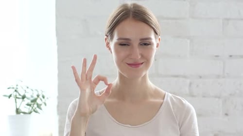Smiling Woman Gives Okay Hand Gesture Indoors