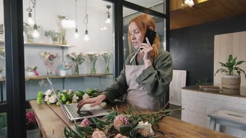 Woman Using Laptop and Phone in Flower Shop