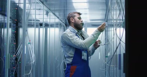 Male Technician Checking Cables in a Data Center