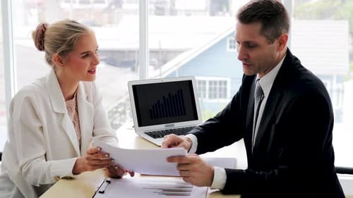 Two confident company employee in suit discussing business ideas presentation on laptop in office
