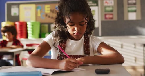 Young Student Smiling While Writing at Desk