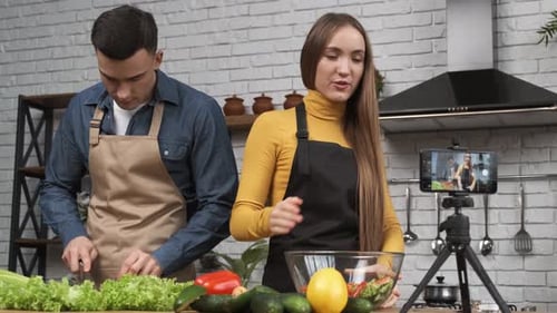 Joven bloguera gastronómica hablando sobre el proceso de preparación de ensaladas y filmando todo el proceso con un