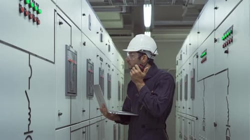 Engineer Using Walkie Talkie with Laptop in Factory