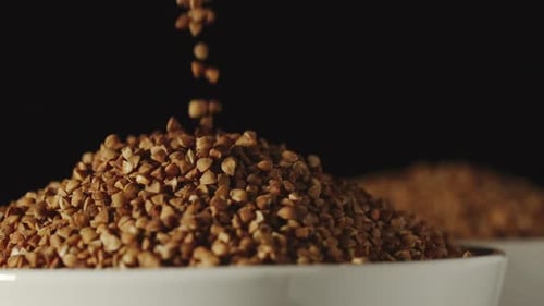 SLOW MOTION Buckwheat Grains Pouring Into A White Bowl - Close Up