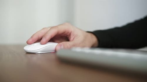 Side View of a Young Man's Hand Using Wireless Computer Mouse Sitting at the Table in the Office