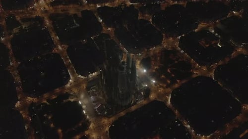 AERIAL: Wide Shot of La Sagrada Familia at Night Glowing in Beautiful Barcelona, Spain