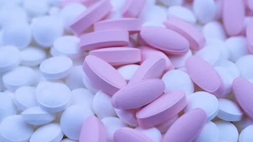 Pink Oval Pills Lie with Small White Round Medicines. Close Up Rotation