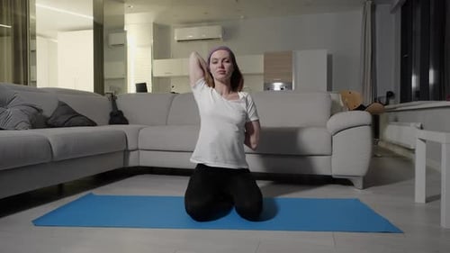 Une fille dans un t-shirt blanc et un pantalon de sport noir faisant du yoga et des étirements