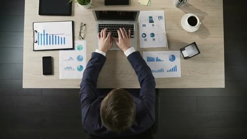 Young Businessman Working on Laptop Computer in Office, Top View of Table