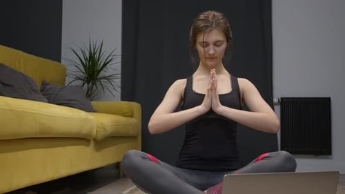 Jeune femme faisant du yoga sur le sol de son appartement