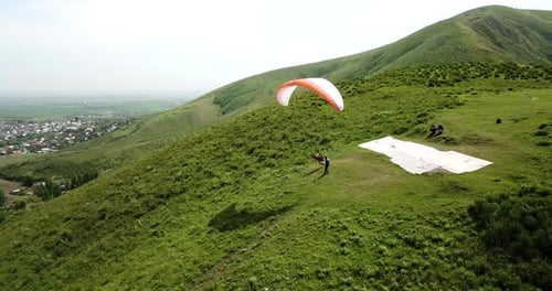 Paraglider Flies Over Green Mountain Village