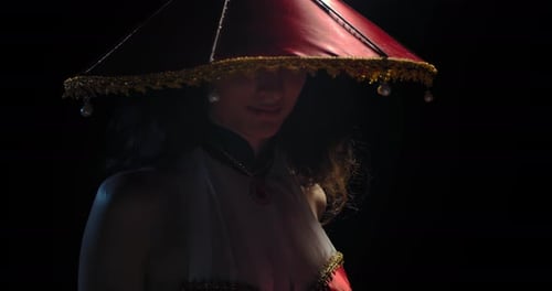 Woman Posing with Elaborate Hat in Dark Lighting