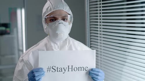 Healthcare Worker in PPE Holding #StayHome Sign