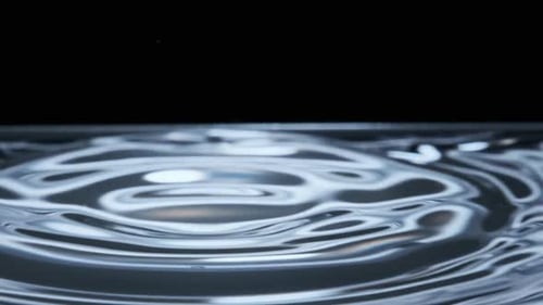 Wassertropfen fallen in Zeitlupen-Makroaufnahme auf die Wasseroberfläche