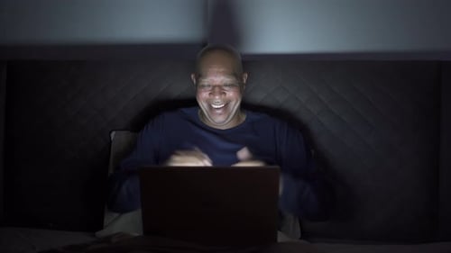 Man Using Laptop in Bed at Night
