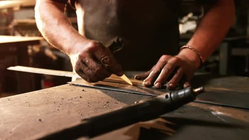 Craftsman Cutting Metal Along Ruler in Golden Light