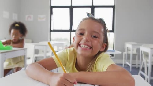Video of happy caucasian girl sitting at school desk and learning