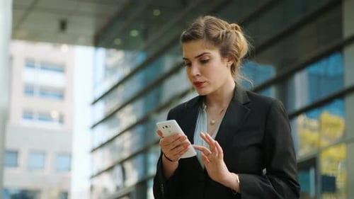 Young business woman walking on the street talking on her mobile phone