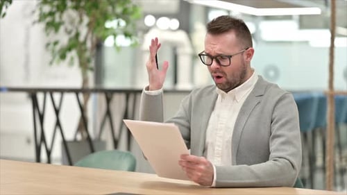 Stressed Man Reviews Documents at Office Desk