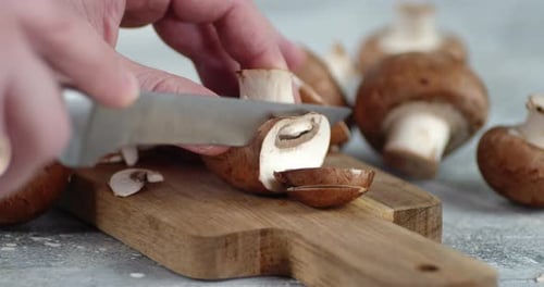 Slicing Fresh Mushrooms on a Wooden Cutting Board