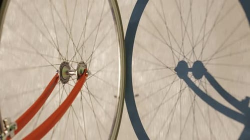 Road bike wheel spinning and casting shadow over a concrete road. Loop animation
