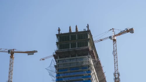 Turmdrehkran auf einer Baustelle hebt eine Last am Hochhaus an. Zeitraffer