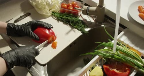 Cutting Bell Pepper On A Board By The Sink With Fresh Vegetables