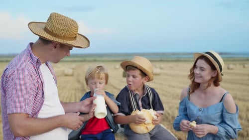 Family at Picnic, Father with Wife and Sons Eat Bread and Wash Down Milk in Wheat Field