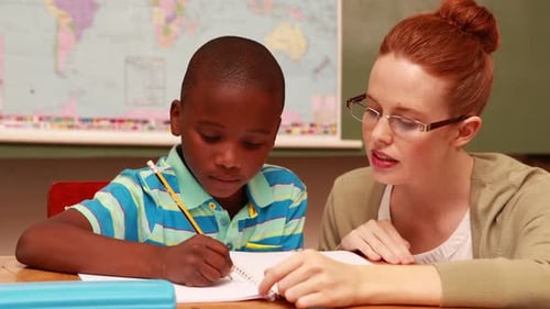 Teacher Helping Young Student with Schoolwork in Classroom