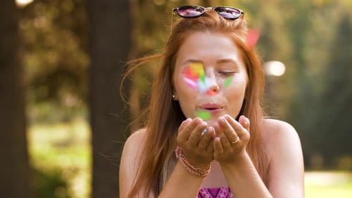 Adolescente soufflant des confettis sur les mains dans le parc