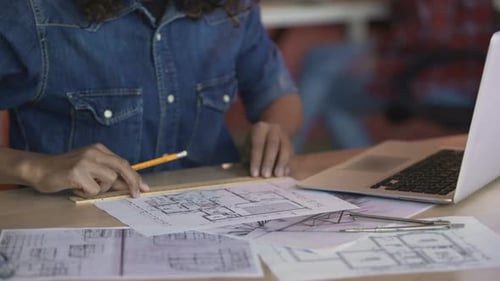 Biracial Designerin arbeitet an Wohnungslayoutplan, Zeichnungslinie auf Papier