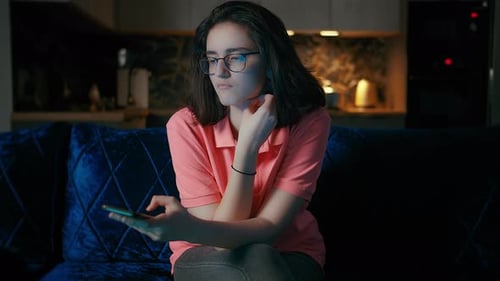 Pensive Young Woman Using Mobile Phone on Couch