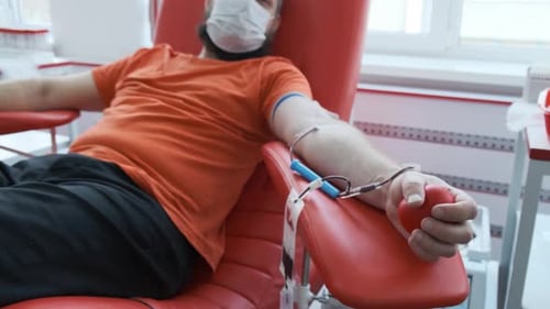 Man Donating Blood in Hospital Sitting in Red Chair
