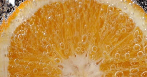 Ein Stück reife Orange unter Wasser mit Luftblasen