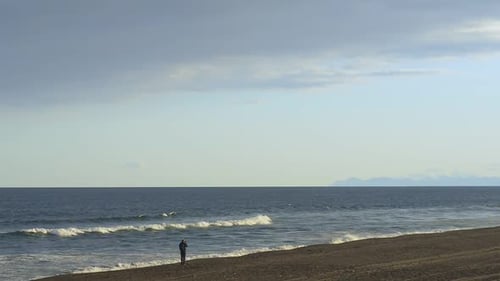 Lone Figure Gazing at the Ocean on Beach