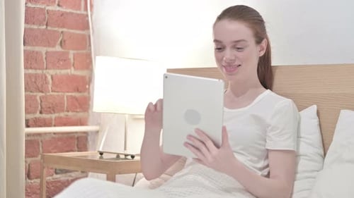 Young Woman Using Tablet in Bed at Home