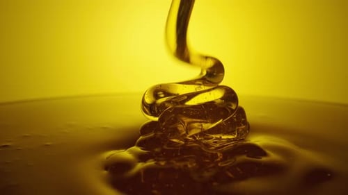 Honey Dripping Pouring Thick Stream on Yellow Background