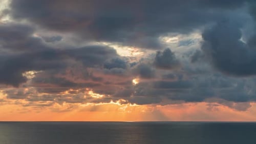 Clouds Crossing Sky Over the Sea Horizon at Sunset with Sun Rays Emerge Through the Storm Clouds