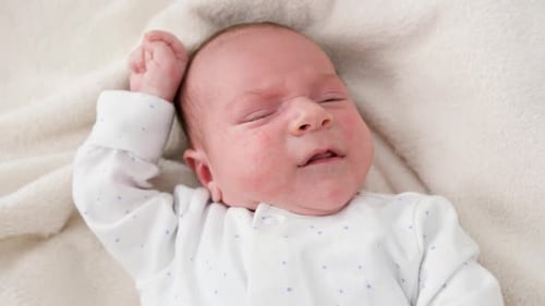 Newborn Infant Crying on White Blanket