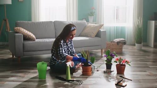 Young Woman Planting Flowers Indoors in Living Room