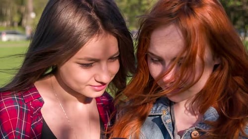 Young Women Viewing Camera Photos in a Park