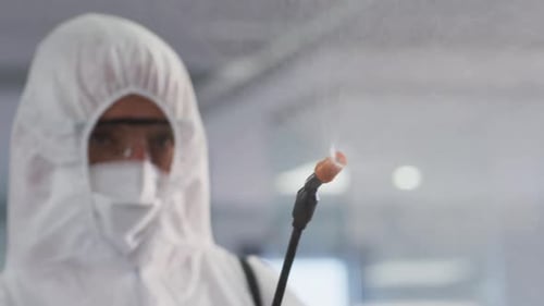 Gesundheitspersonal in Schutzkleidung reinigt das Büro mit Desinfektionsmittel
