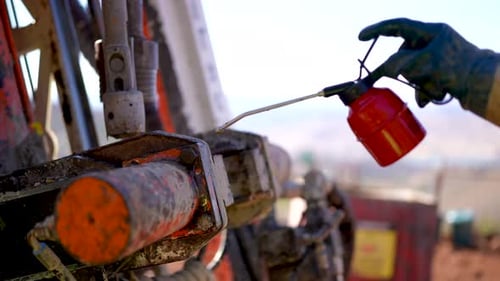Gold Mine Worker Squeezes Oil on Drilling Rig Screws