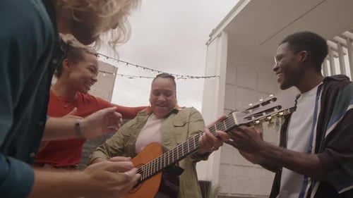 Friends Singing and Playing Guitar on Rooftop